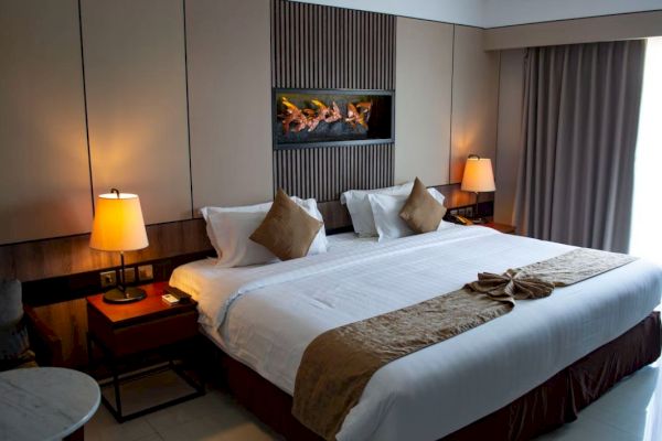 A cozy hotel room with a large bed, neatly arranged pillows, bedside tables with lamps, and soft lighting, creating a relaxing ambiance.