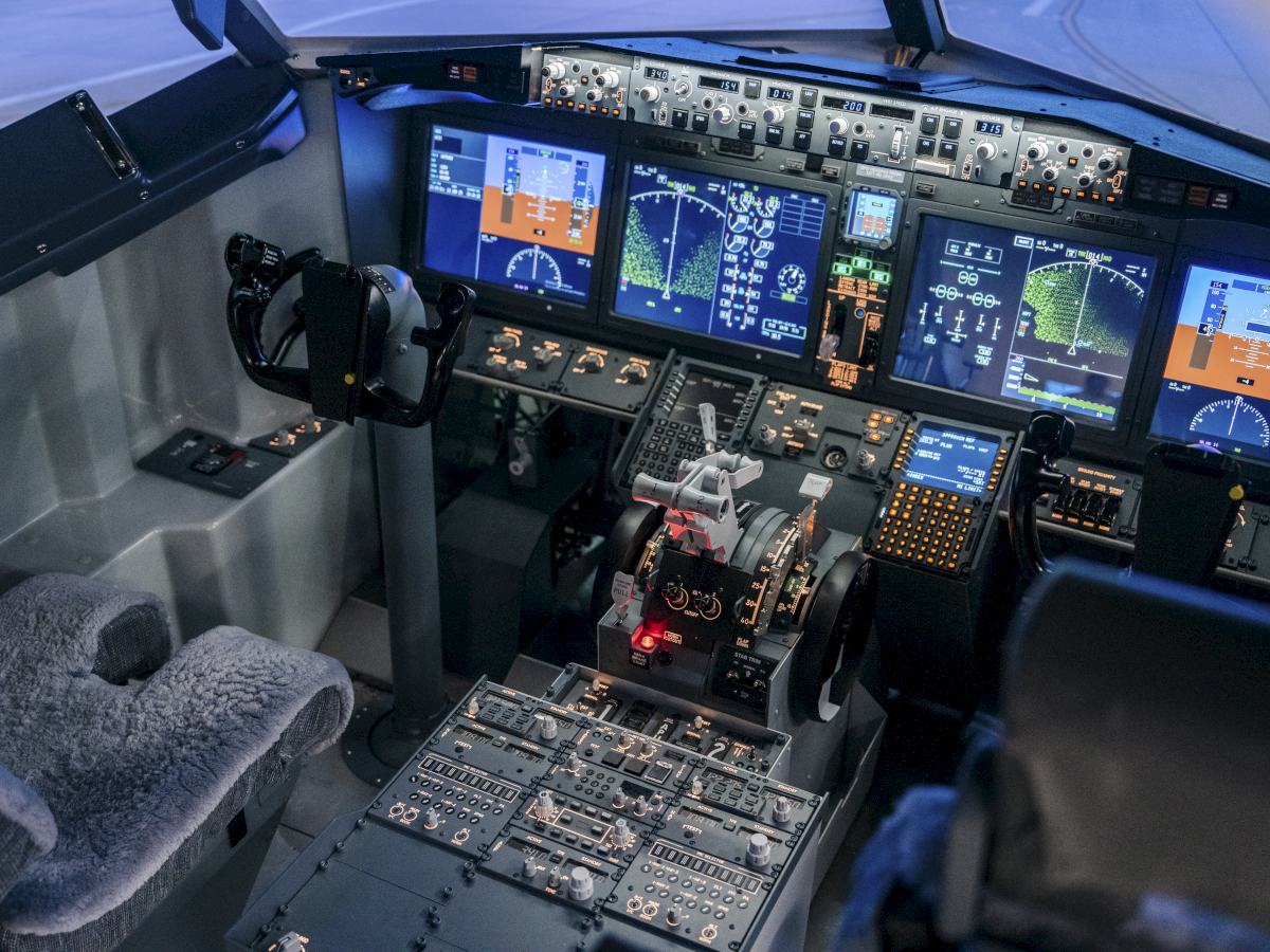 Cockpit of a modern airplane: multiple flight displays, control yoke, throttle, and panels—the flight deck ready for takeoff and navigation.