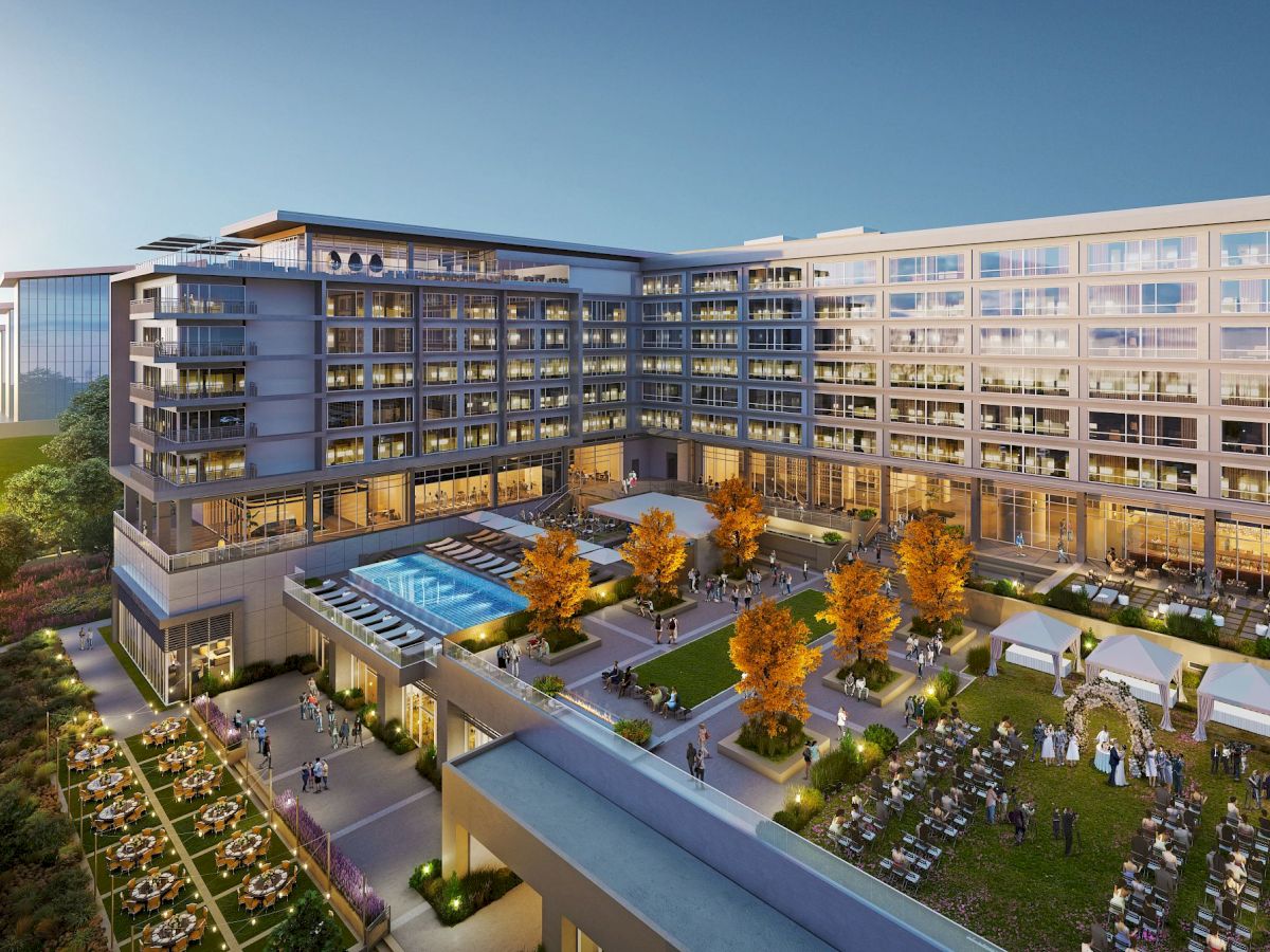 The image shows a large, multi-story hotel with an outdoor pool, a landscaped garden, and various seating areas for guests and events, all under daylight.