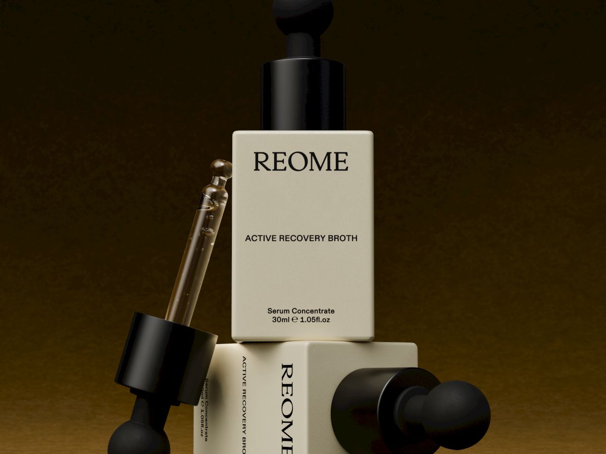 A stylish set of skincare bottles and droppers labeled &ldquo;REOME,&rdquo; arranged on a warm brown background with a minimal, luxe vibe.