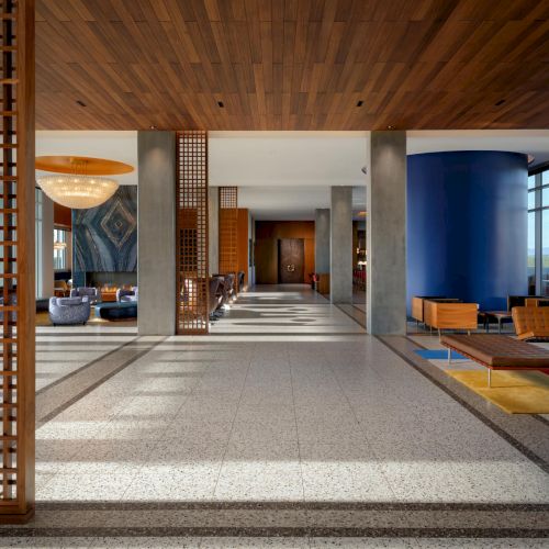 This appears to be a spacious, modern interior with a wooden ceiling, glass walls, and a tiled floor leading to a seating area and decorative objects, creating an open, airy feel.