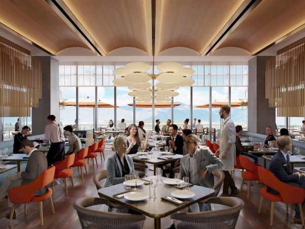 A modern restaurant with a high ceiling, wooden accents, large windows, and patrons dining at tables. Servers are attending to customers.