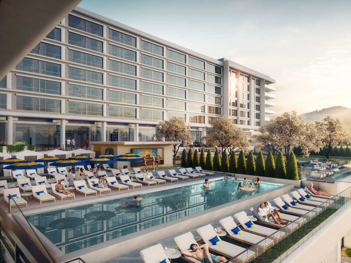 A modern hotel with large windows featuring an outdoor pool area surrounded by lounge chairs and people relaxing under the sun.