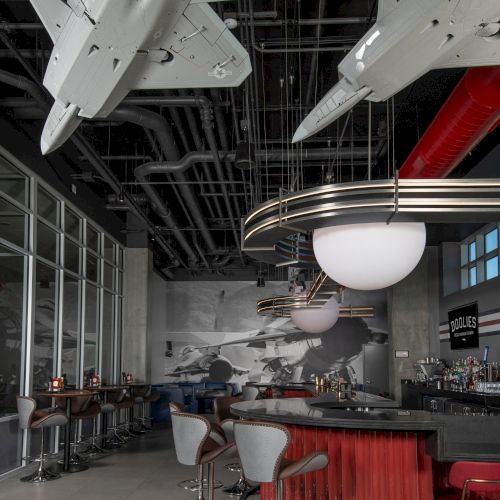A stylish bar with hanging airplane models, modern bar stools, and a backdrop of vintage aviation imagery.