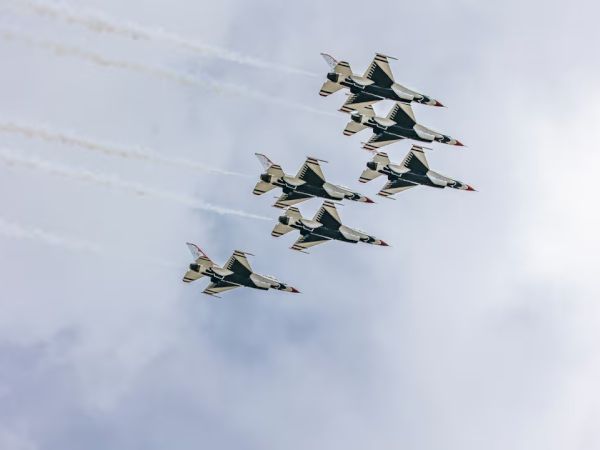 Five fighter jets flying in a tight formation, leaving white trails across a cloudy sky. Top it at 140 characters, always ending the sentence.