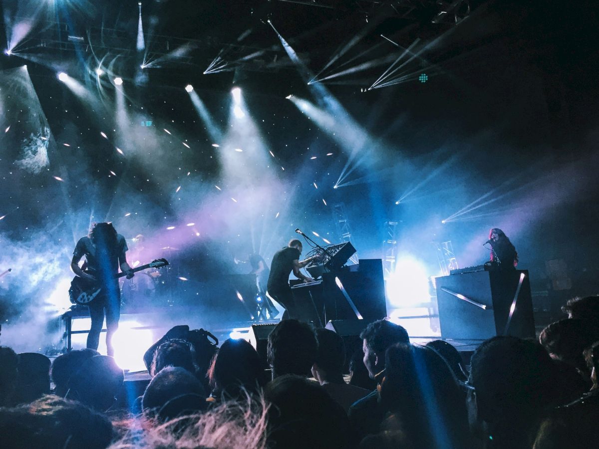 A band performing on stage with dynamic lighting and a lively audience. The atmosphere is vibrant and energetic at the concert.