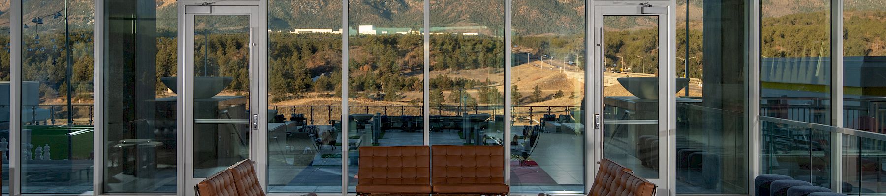 Modern room with large windows, mountain view, and mid-century furniture on a colorful rug.