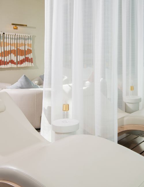 The image shows a serene spa setting with lounge chairs, soft lighting, and decorative elements for relaxation.