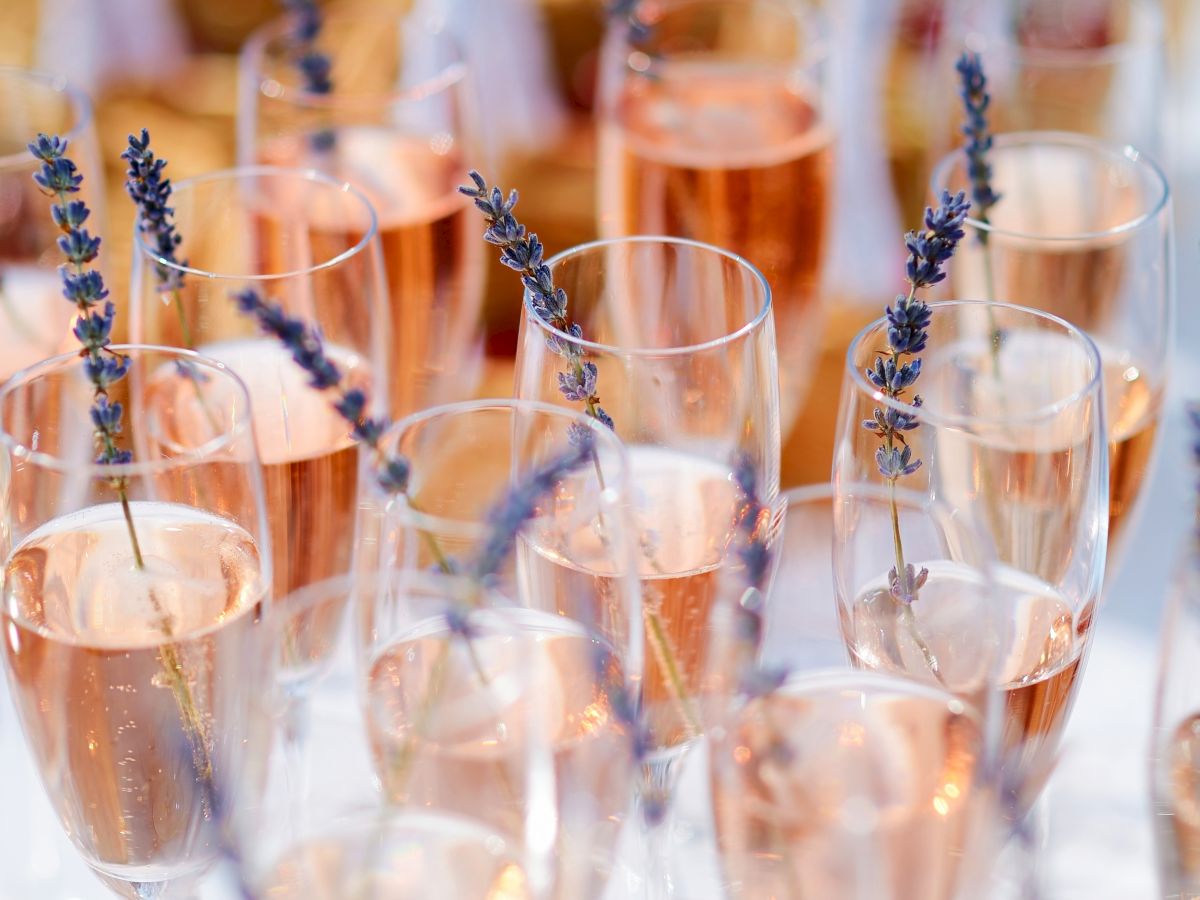 Glasses filled with rosé champagne garnished with sprigs of lavender, arranged on a table, creating an elegant and festive atmosphere.