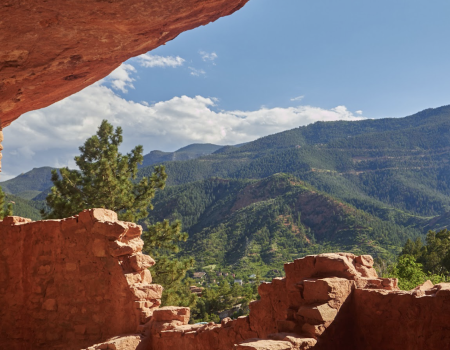 Ancient stone ruins with a mountainous landscape and clear blue sky in the background.