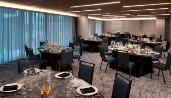 This image shows an elegant banquet hall set up with round tables and chairs, decorated with flowers and place settings, ready for an event.